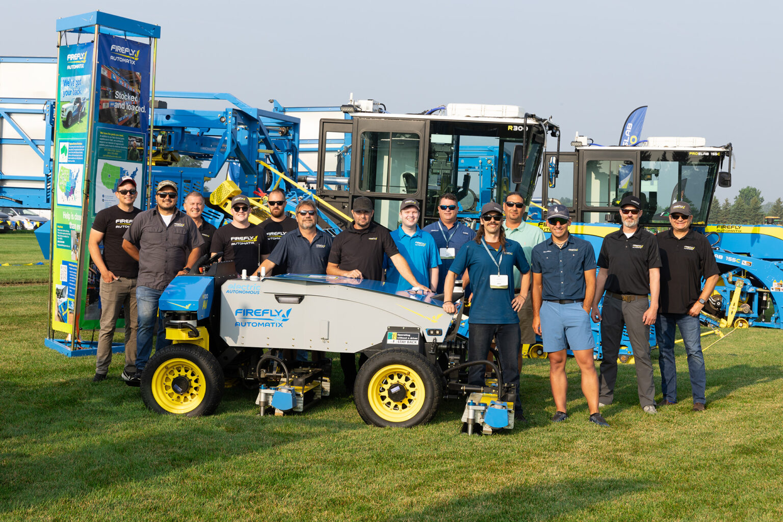 Several team members standing around FireFly Automatix autonomous lawn ower and sod harvesters