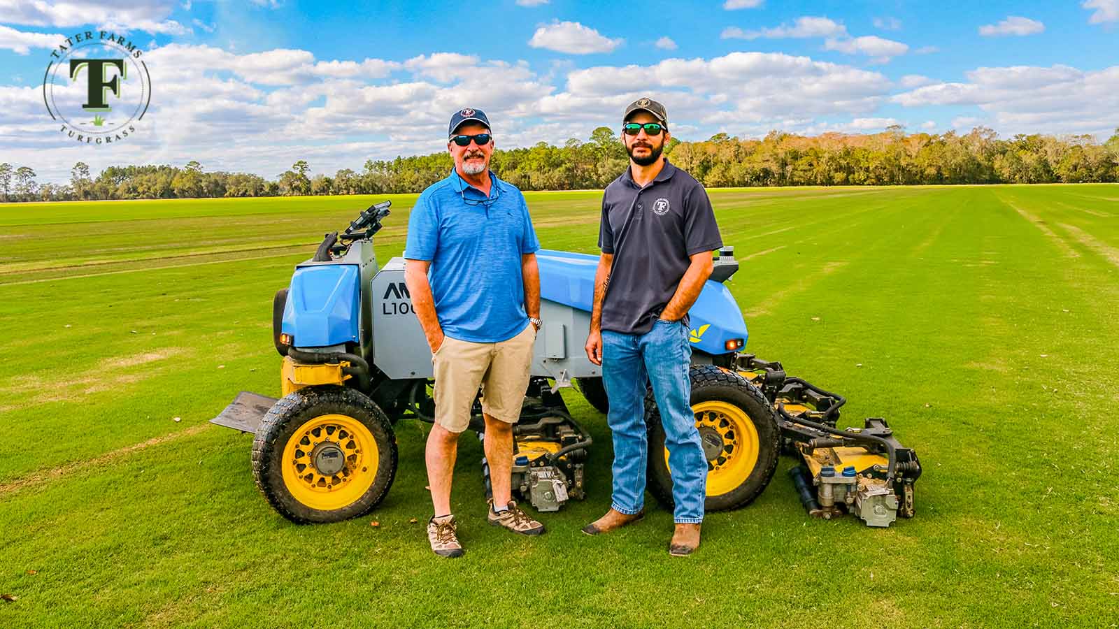 Eric Hjort and Gage Hjort in front of FireFly autonomous mower in grass field at Tater Farms