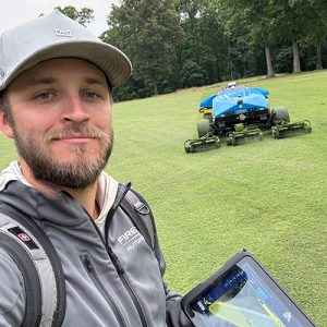 Jack Anderson holding tablet with FireFly AMP mower in background