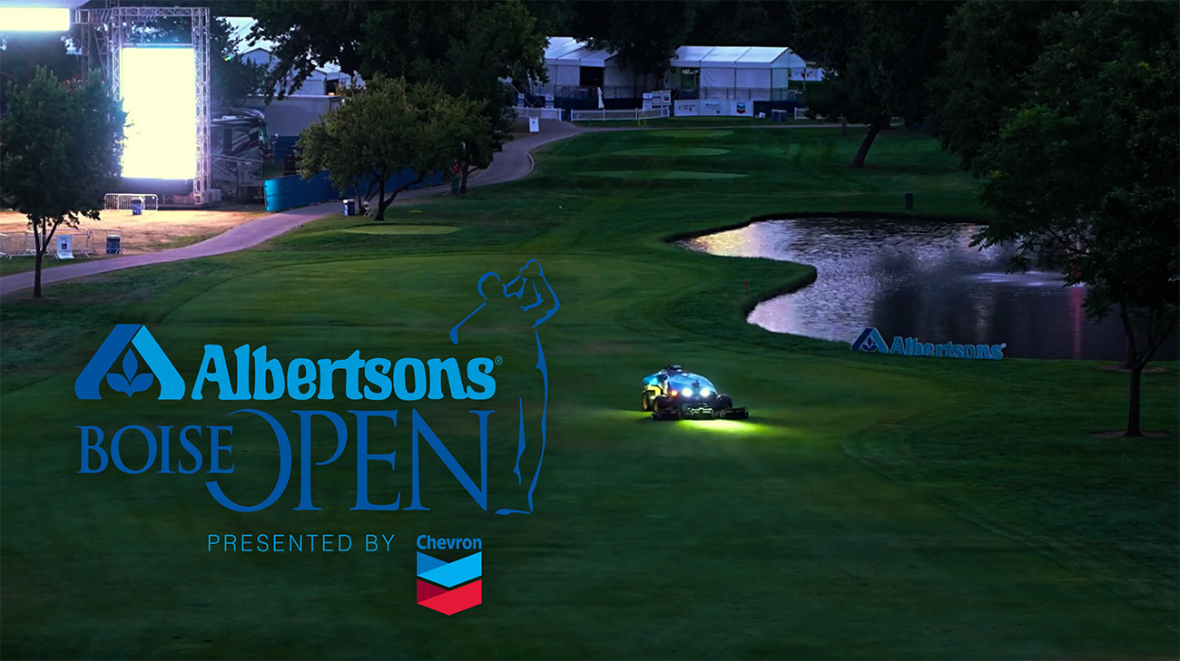FireFly Automatix mowers on a dark golf course with a water hazard and tournament structures in background, Albertsons Boise Open logos