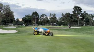 FireFly autonomous fairway mower on golf course with workers in the background