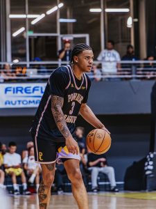 NBA Utah Jazz player Keyonte George in a jersey with FireFly Automatix logo and signage behind him, holding a basketball on a court