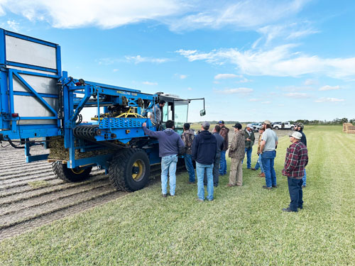 FireFly harvester in green farm field wit people gathered around the operator