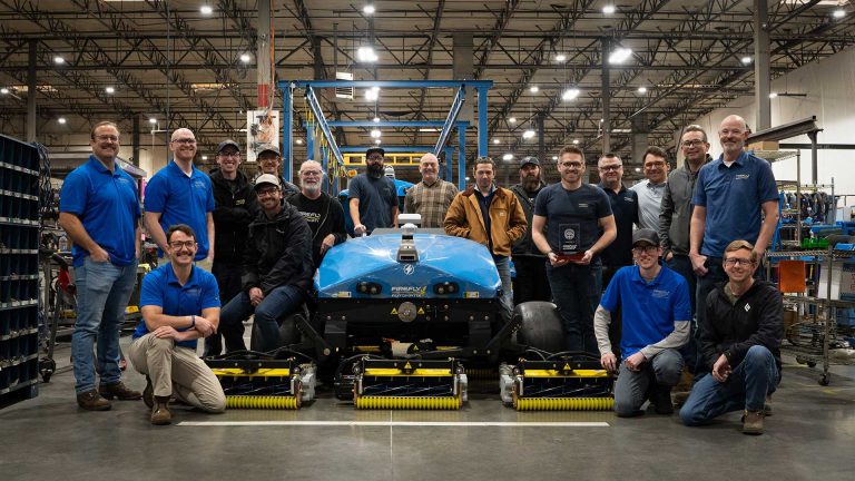 Group of FireFly Automatix engineers at the Salt Lake City production facility holding the SFMA Innovator Award beside a newly completed autonomous mower